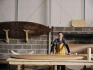 Ritratto di uomo in piedi davanti al paddleboard in legno fatto a mano in officina — Foto stock