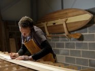 Paddleboard-Hersteller nutzt Handy in Werkstatt — Stockfoto