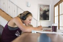 Teenage girl at home wearing headphones as painting, side view. — Stock Photo