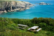 Mesas de piquenique de madeira no penhasco em Pembrokeshire Coast, País de Gales, Reino Unido . — Fotografia de Stock