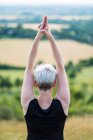 Rear view of woman practicing outdoor yoga on hillside. — Stock Photo
