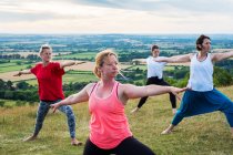 Group of women taking part in outdoor yoga class on a hillside. — Stock Photo