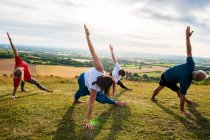Gruppo di donne e uomo che partecipano a lezioni di yoga all'aperto su una collina . — Foto stock