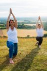 Deux femmes prenant part à un cours de yoga en plein air sur une colline . — Photo de stock