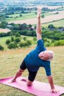 Uomo anziano che partecipa a lezione di yoga all'aperto su una collina . — Foto stock