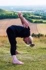 Seniorin nimmt an Outdoor-Yoga-Kurs am Hang teil. — Stockfoto