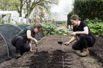Two women working on freshly laid bed of soil in a vegetable garden. — Stock Photo