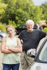 Старший дедушка и внучка-подросток позируют, когда мыли вместе машину на подъездной дорожке — стоковое фото