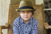Портрет мальчика, сидящего в плетеном кресле — стоковое фото