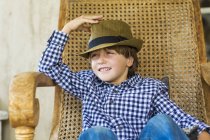 Портрет маленького хлопчика, що сидить у плетеному кріслі — стокове фото