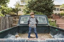 Portrait of elementary age boy posing in bed of old pick up truck — Stock Photo