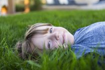 Retrato do menino pré-adolescente sorridente deitado na grama verde — Fotografia de Stock