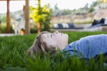 Portrait of smiling pre-teen boy lying down in green grass — Stock Photo