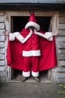 Man wearing Santa Claus costume standing in workshop doorway. — Stock Photo