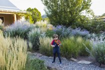 Ragazzo in età elementare che suona il violino fuori in giardino — Foto stock