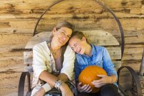 Portrait of mother and teenage daughter holding pumpkin in barn — Stock Photo