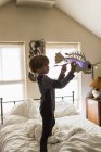 Маленький мальчик играет с рыбной игрушкой на кровати — стоковое фото