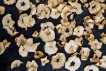 High angle close-up of dried slices of apple on dark background. — Stock Photo
