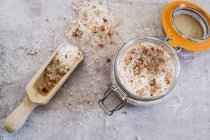 High angle close-up of wooden spoon and glass jar with coarse salt. — Stock Photo