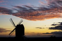 Moulin à vent au coucher du soleil sous un ciel nuageux romantique . — Photo de stock
