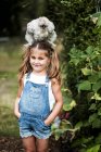 Sorridente ragazza bionda in piedi in giardino, con soffice pollo grigio sulla testa . — Foto stock