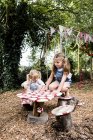 Due ragazze sedute a tavolino in legno in giardino e a giocare . — Foto stock