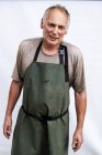 Portrait of male farmer wearing green apron smiling in camera. — Stock Photo