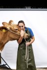 Portrait of female farmer wearing green apron kissing Guernsey cow. — Stock Photo