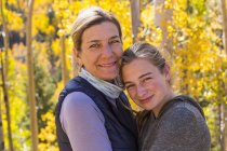 Portrait of mother and teenage daughter with autumn aspens in woods — Stock Photo