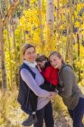 Mature mother with boy and girl posing in woodland with aspen trees in autumn foliage — Stock Photo