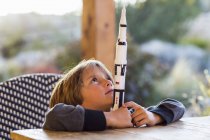 Junge im Grundalter spielt mit Spielzeugrakete und träumt vom Raumflug. — Stockfoto