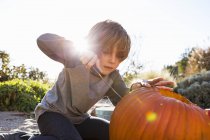 Junge im Grundschulalter schnitzt zu Halloween im Freien Kürbis. — Stockfoto