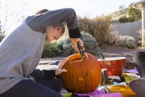 Menino da idade elementar esculpindo abóbora ao ar livre no Halloween . — Fotografia de Stock