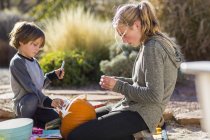 Teenage girl and elementary age boy carving pumpkin at Halloween. — Stock Photo