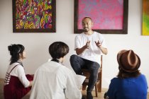 Grupo de homens e mulheres japoneses sentados na galeria de arte, ouvindo o artista masculino realizando discussão . — Fotografia de Stock