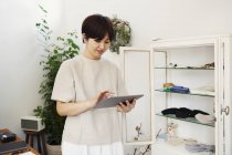 Японская женщина, стоящая в маленьком модном бутике, смотрит на цифровой планшет
. — стоковое фото