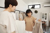 Duas mulheres japonesas em pé em uma pequena boutique de moda, olhando para o topo . — Fotografia de Stock