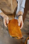 High angle close-up of person holding an leather purse in artisan store. — Stock Photo
