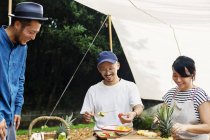 Uomini e donne giapponesi riuniti intorno a un tavolo sotto un baldacchino, preparando frutta fresca . — Foto stock