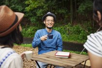 Japaner und Frauen sitzen draußen an einem Tisch und trinken Kaffee. — Stockfoto