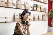 Mujer japonesa profesional usando sombrero y auriculares, sentada en un espacio de co-trabajo . - foto de stock