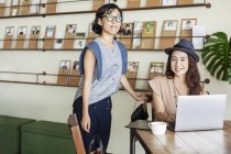 Two female Japanese professionals at a table in a co-working space, using laptop computer. — Stock Photo