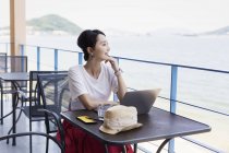 Japanese businesswoman sitting on balcony of a co-working space, using laptop computer. — Stock Photo