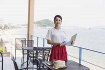 Japanische Geschäftsfrau steht mit Laptop auf dem Balkon eines Co-Working Space. — Stockfoto