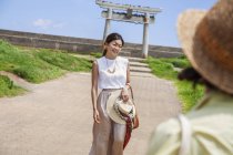 Two Japanese women wearing hats standing on a path, taking picture. — Stock Photo