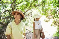 Zwei japanische Frauen mit Hüten wandern in einem Wald. — Stockfoto