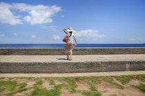 Mulher japonesa usando chapéu de pé em uma parede por oceano . — Fotografia de Stock
