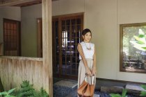 Japanerin steht auf einer Veranda und hält Handtasche. — Stockfoto