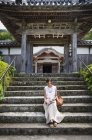 Японская женщина сидит на ступеньках перед буддийским храмом . — стоковое фото