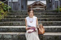 Japanerin sitzt auf Stufen vor einem buddhistischen Tempel. — Stockfoto